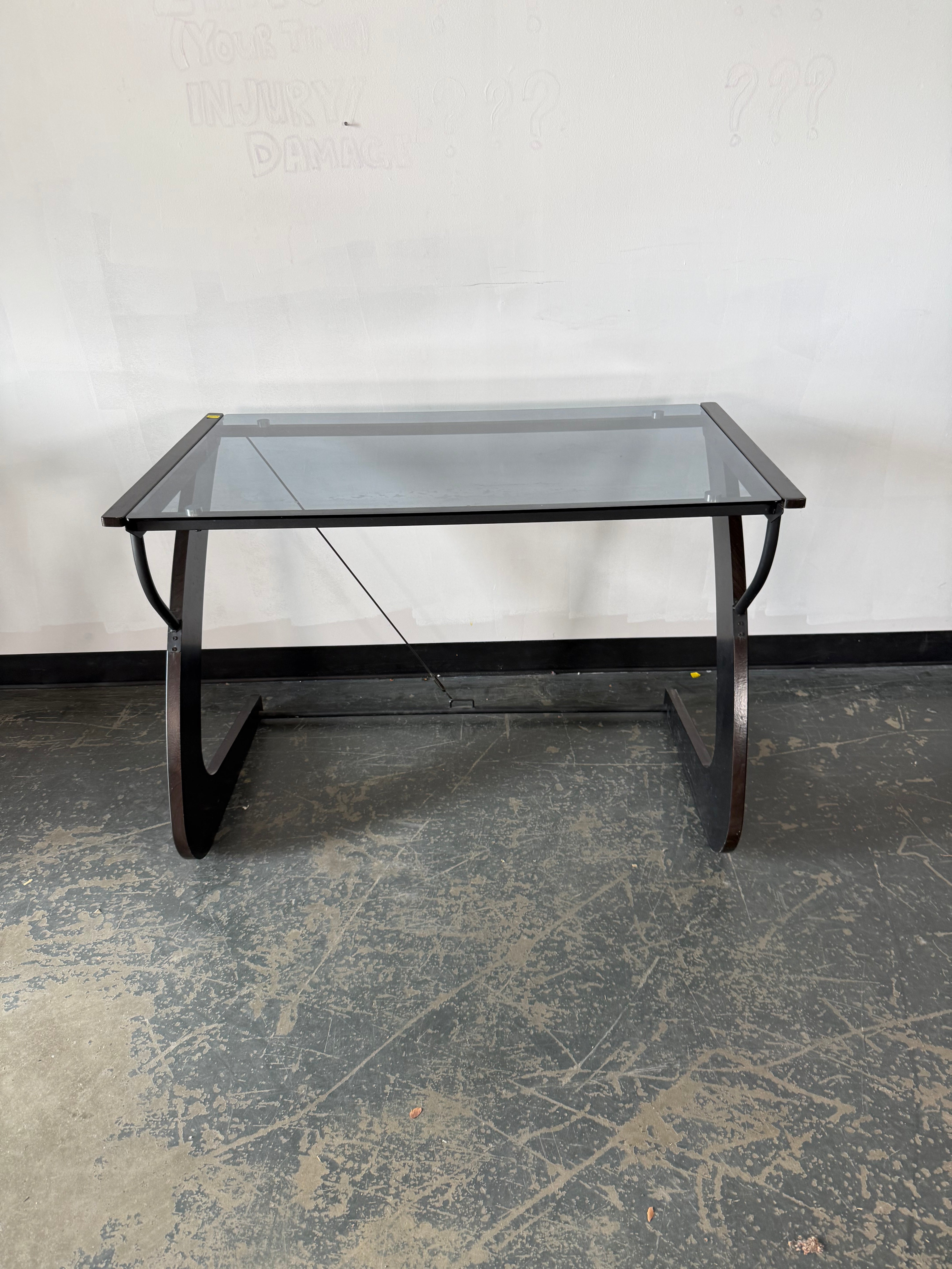 Glass coffee table with metal frame on a textured floor against a white wall