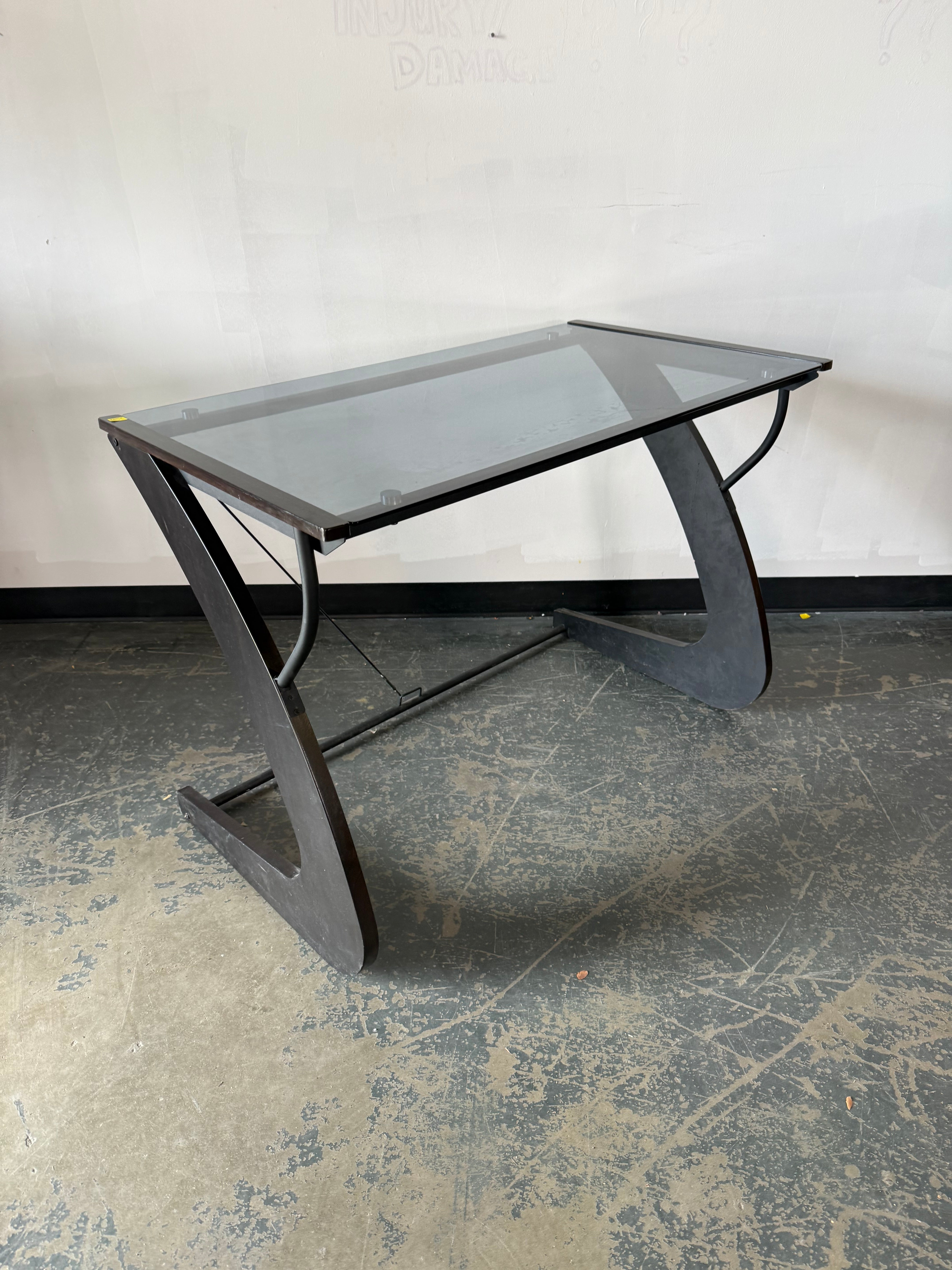 Glass coffee table with metal frame on a textured floor against a white wall