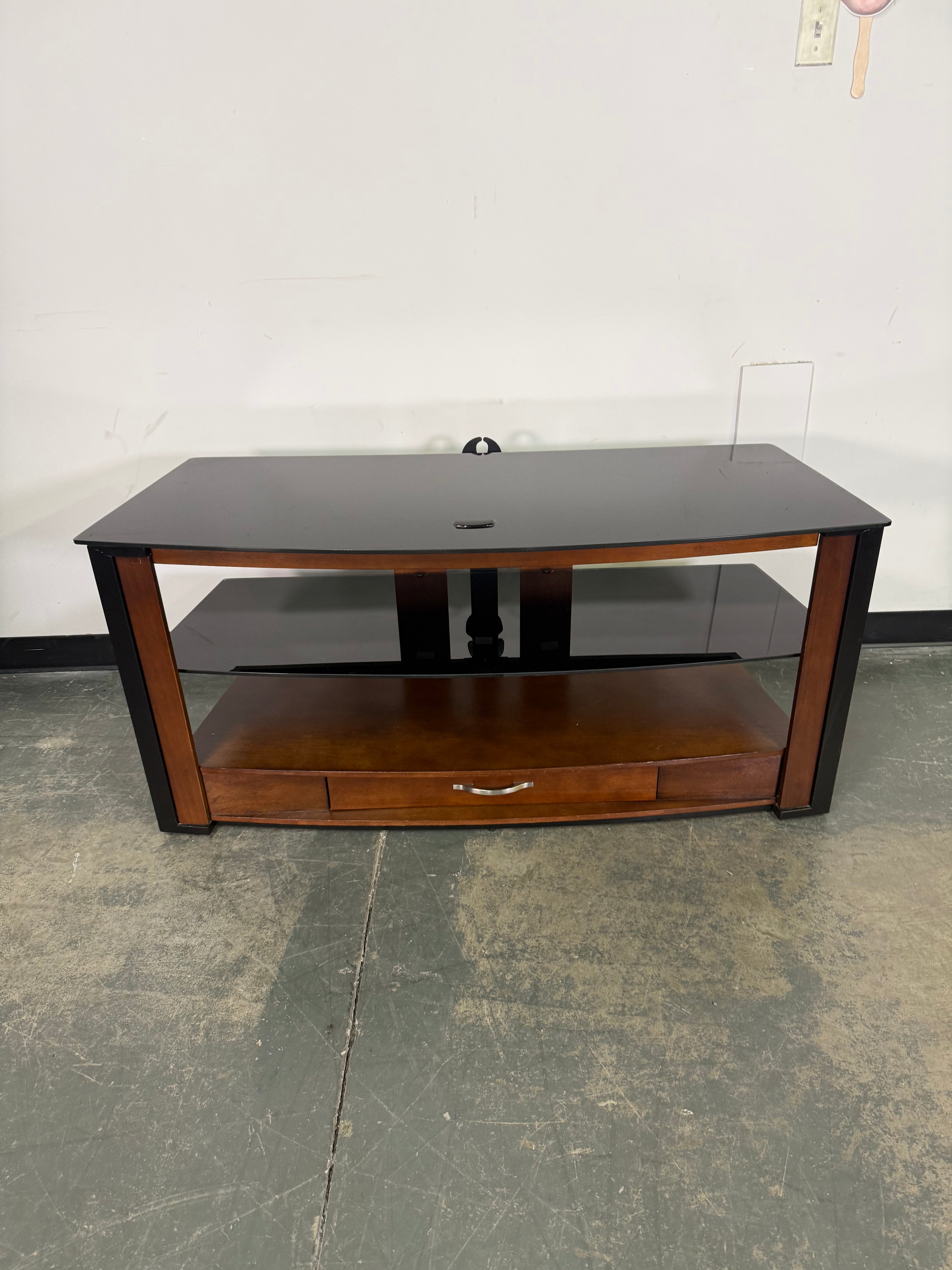 Wooden cabinet with glass doors on a white wall and gray floor.