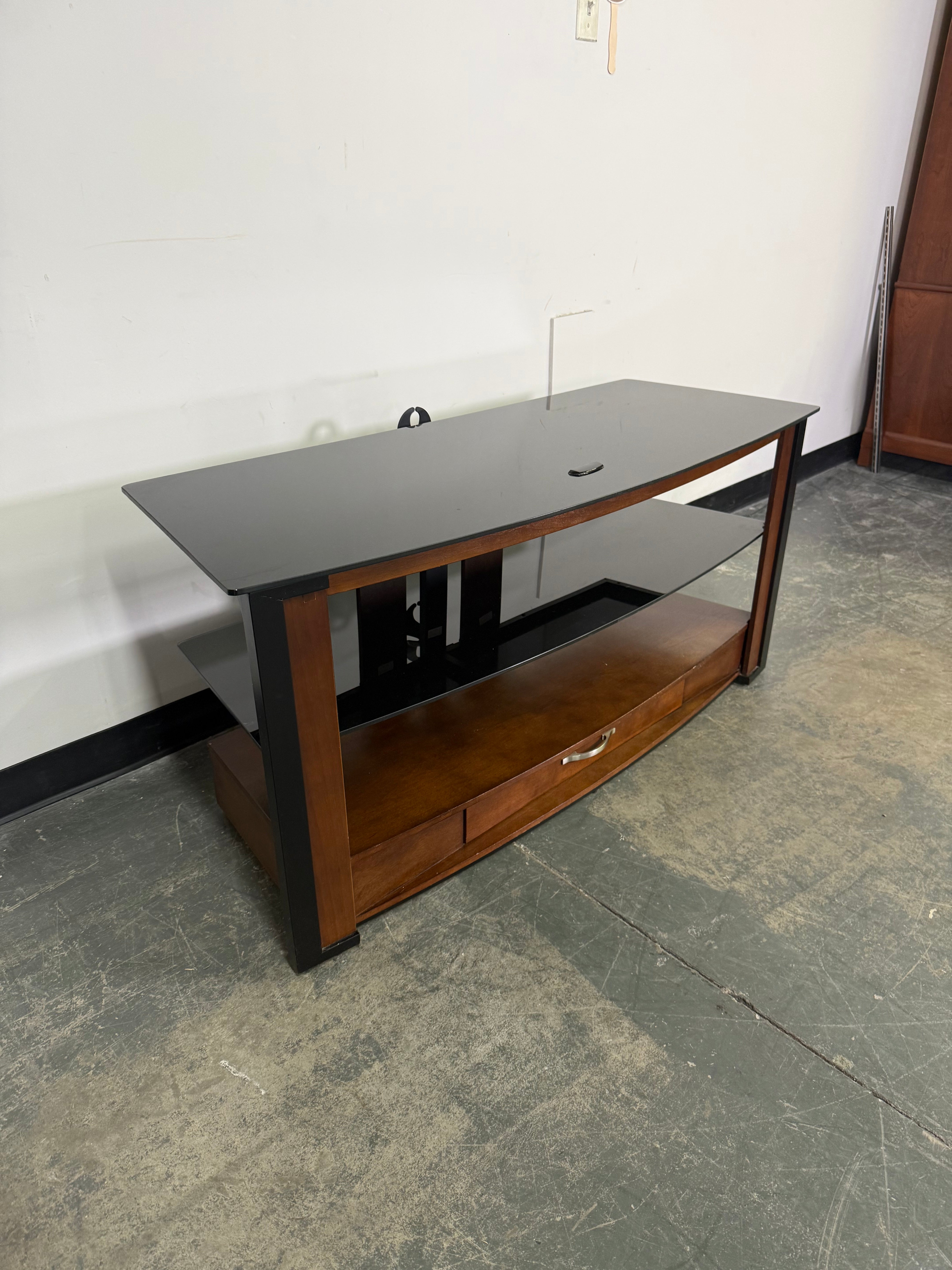 Wooden cabinet with glass doors on a white wall and gray floor.