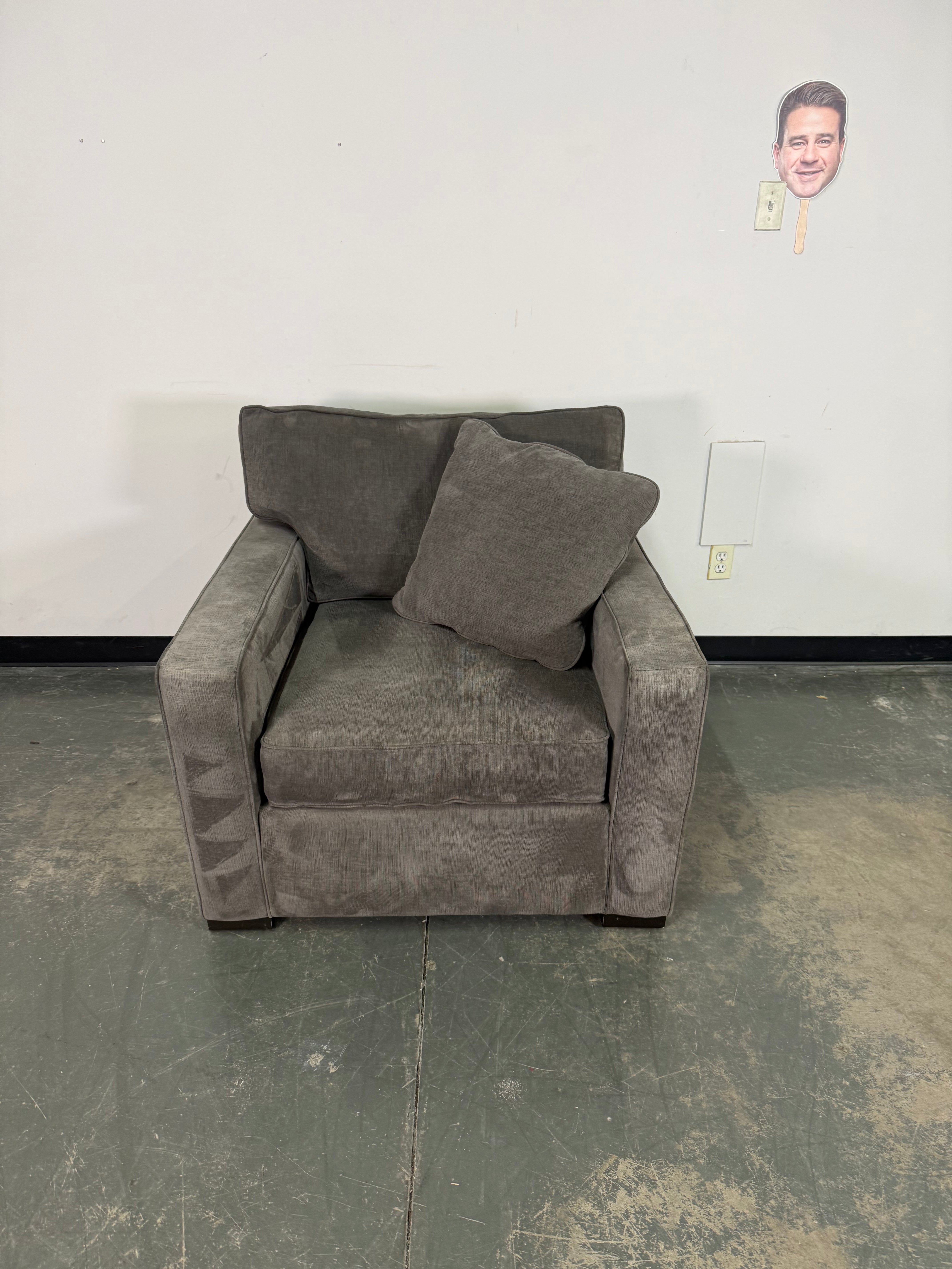 Gray armchair in a room with a plain wall and floor.