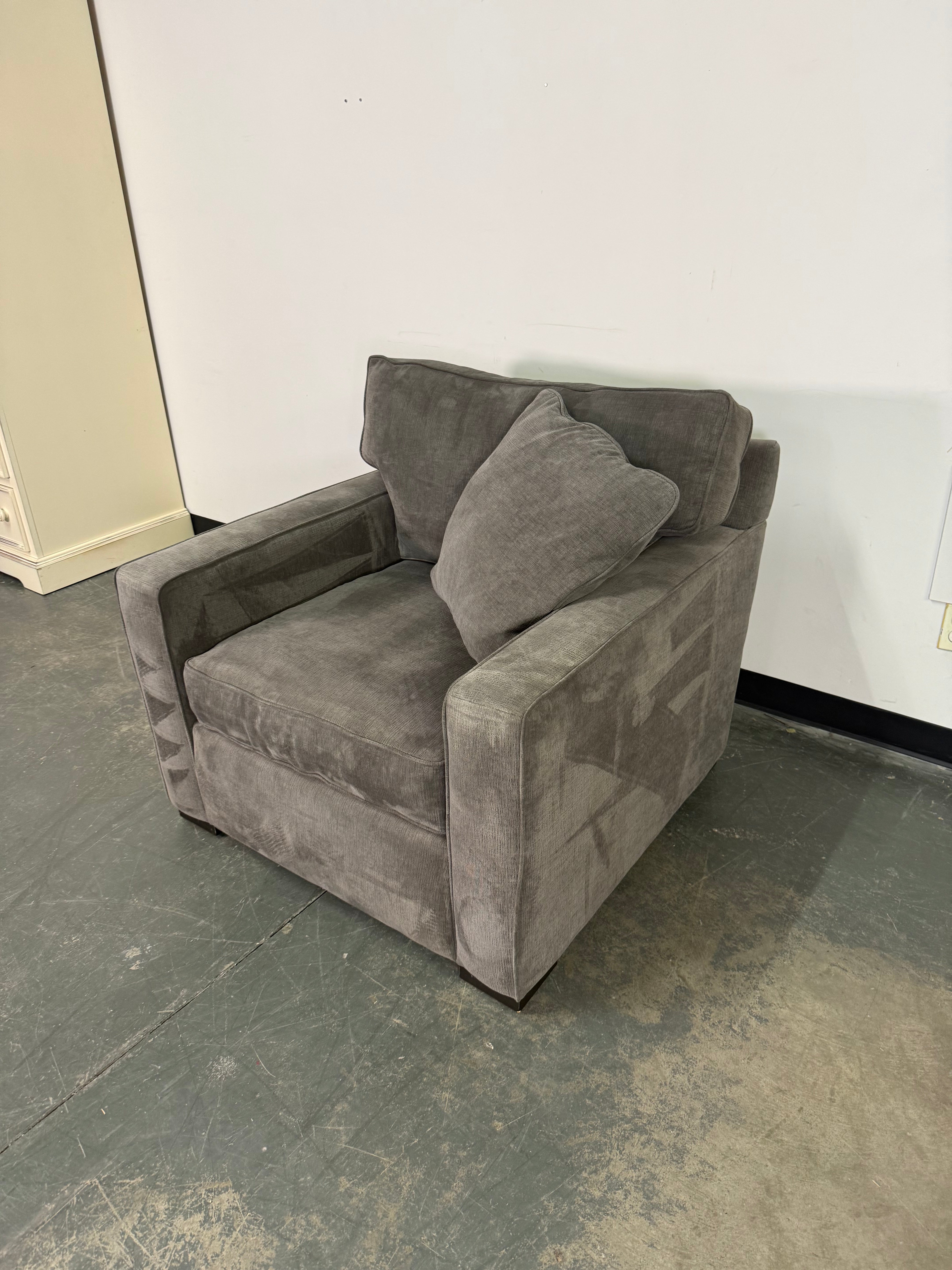 Gray armchair in a room with a plain wall and floor.