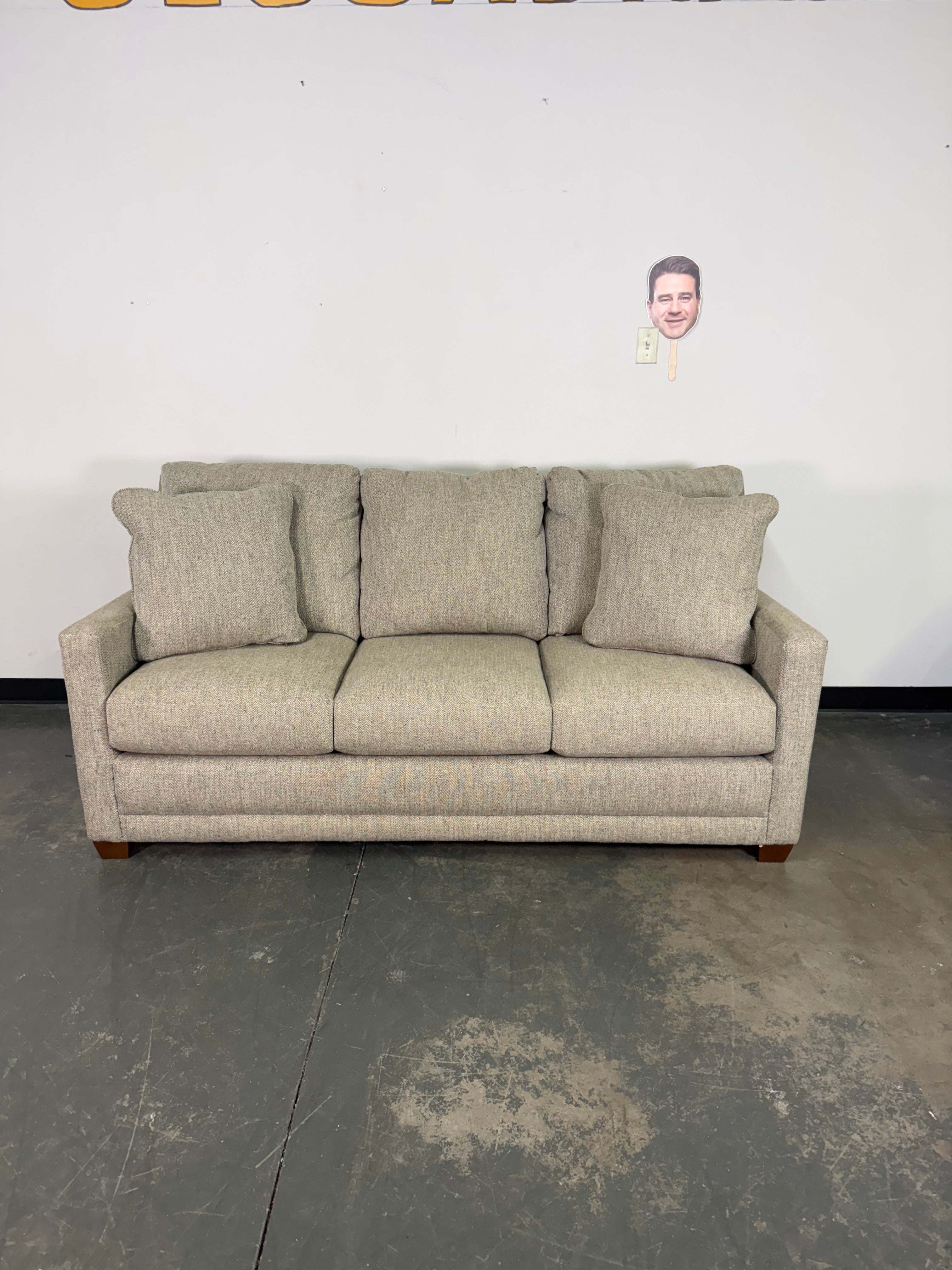 Beige sofa against a white wall with a dark floor.